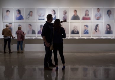 two people standing looking at portraits on wall