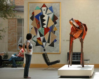 A person standing looking at a red horse sculpture inside