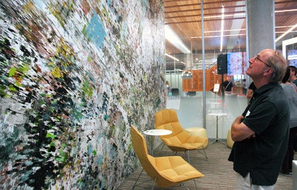 person looking at wall with yellow chairs behind them