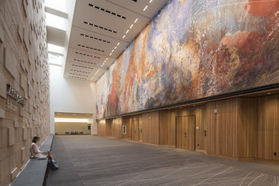 person sitting on bench below sky lights in big atrium