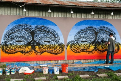 person standing off right of frame painting mural on wall