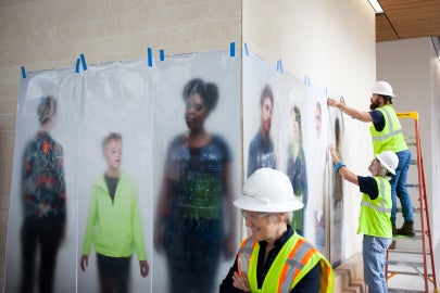 people holding photos up against a wall
