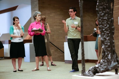 people standing and talking in front of sculpture