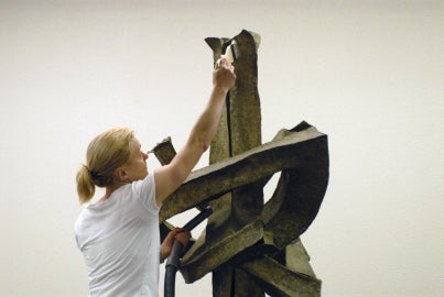 person reaching up high to touch sculpture