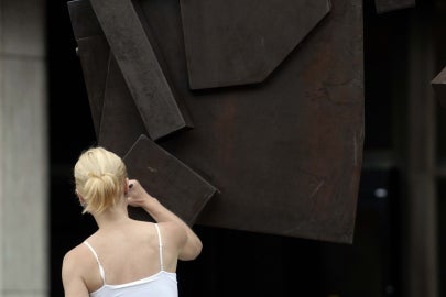 back of person raising hand to sculpture
