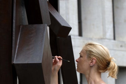 person holding right hand up against sculpture