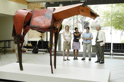 red horse sculpture with people walking by in the background