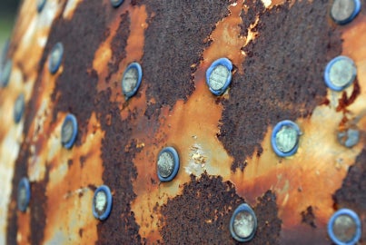 A rusted spherical surface with pennies adhered to it