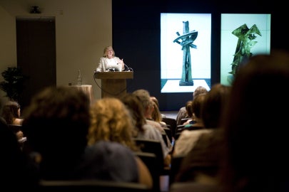 woman in back left speaking at podium