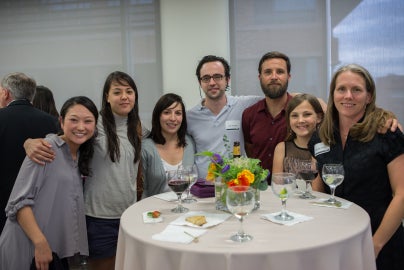 seven people standing around a table 