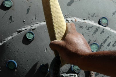 hand holding rope in front of gray sculpture