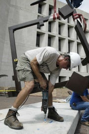 Man leaning over drilling into white platform 