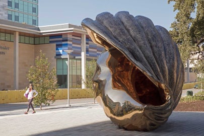 A large bronze shell with a woman walking by