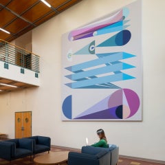 A person sitting on a couch in front of a large geometric painting