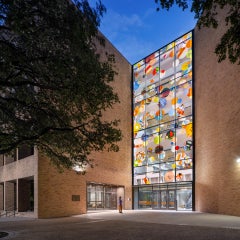 A person in front of a building with a glass facade full of colorful circles