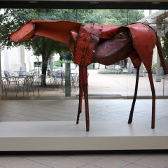 A red horse sculpture in front of a large window