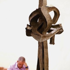 A man reading behind a large vertical sculpture