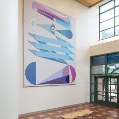 An image of Eamon Ore-Giron's "Tras los ojos," a large digital print which hangs in the atrium of a building.