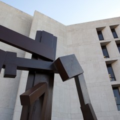 flat brown surface sculpture up against limestone building