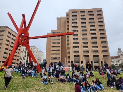 A crowd of young students under Mark di Suvero's "Clock Knot"