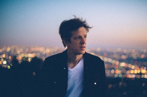 A headshot of Britt Daniel in front of a hazy sunset. 
