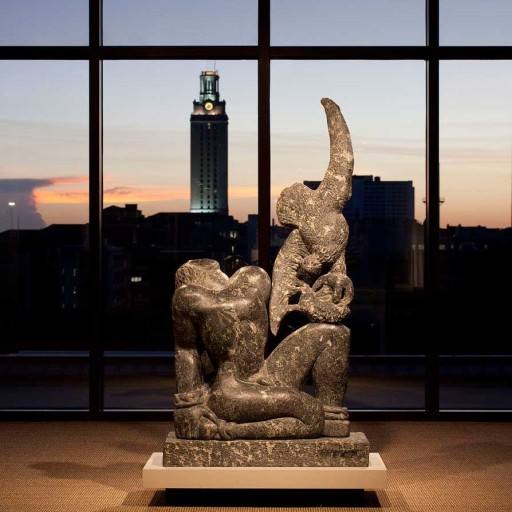 A sculpture in front of a large window with a tower in the background