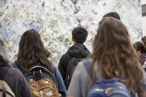 photo of students looking at a work of art that contains grey, blue, and green streaks of color across a wall