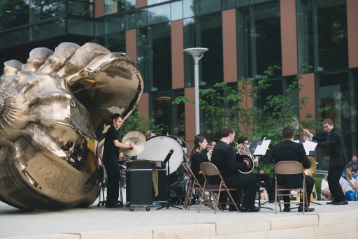 Musicians playing in front of bronze sculpture of shell