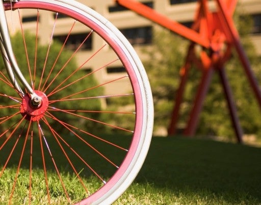 A red bike wheel can be seen in front of Mark di Suvero's "Clock Knot"