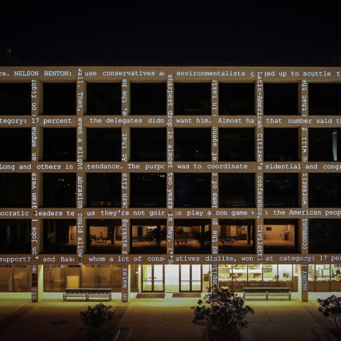 A grid-like building which has text projected across the facade. 