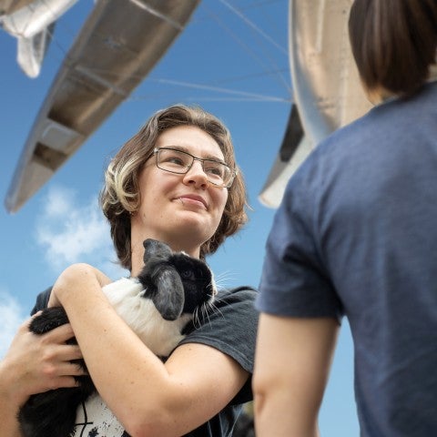 A photograph of a student holding a rabbit under Nancy Rubins' "Monochrome for Austin"