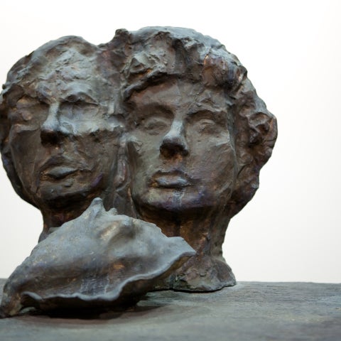 a bronze bust of two heads with a bronze conch in the foreground