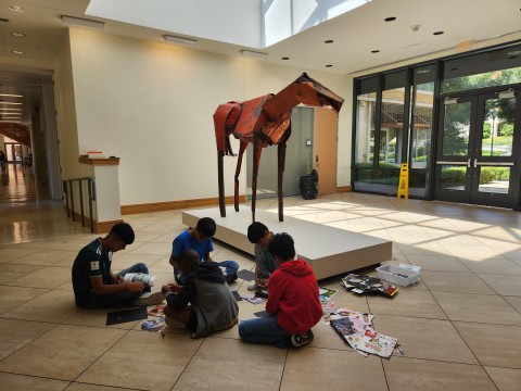 A group of students collage in front of Deborah Butterfield's "Vermillion" a horse sculpture assembled from scrap metal.