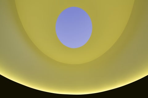 A curved room is lit yellow, while an open oculus in the ceiling reveals a lavender sky.