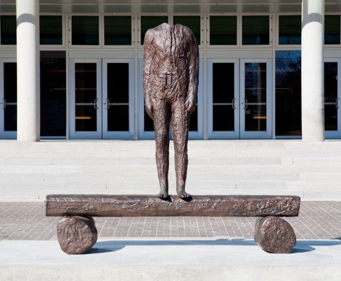 Headless statue in front of a large building