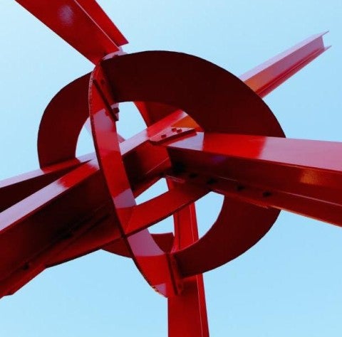 Mark di Suvero, Clock Knot Red metal sculpture with a clear sky in the background.