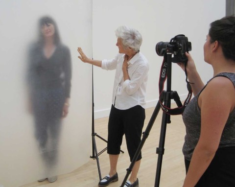 A woman photographing a subject behind a semi-opaque screen