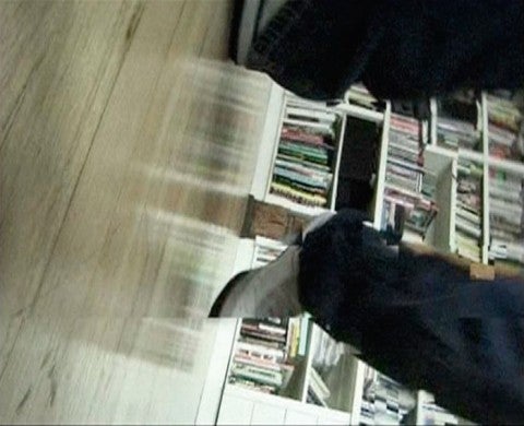 Douglas Gordon, Domestic, 2002 A sideways leg in front of a bookshelf
