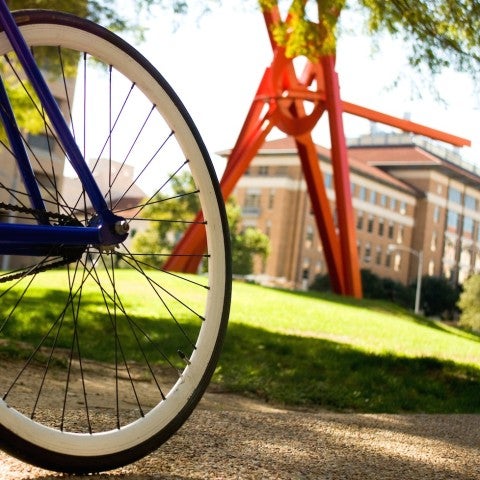 The wheel of a bicycle in front of a metal sculpture