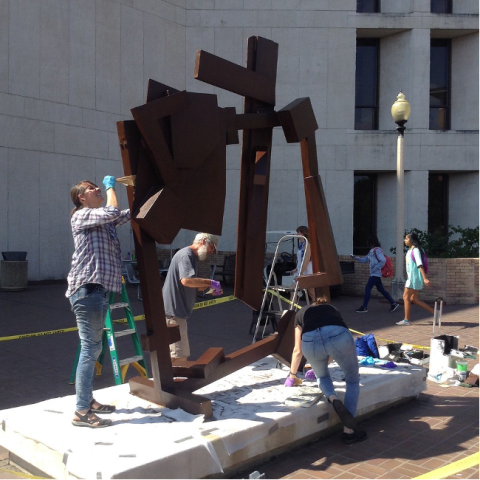 A picture of conservators working on a sculpture outside of the PCL Library on campus