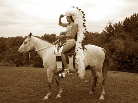 Kent Monkman, Group of Seven Inches, 2005 A man in a long Native American headdress and large pumps sitting on a horse