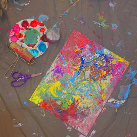 picture of paint splattered on canvas with art materials surrounding it
