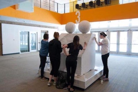 students cleaning marble sculpture