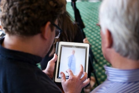 two men looking at photos on a ipad