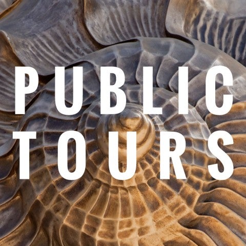 Tourmembers standing in front of a brown outdoor sculpture