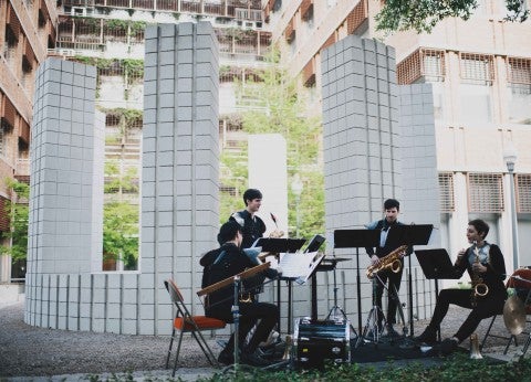 A group of musicians perform in front of Sol LeWitt's "Circle with Towers"