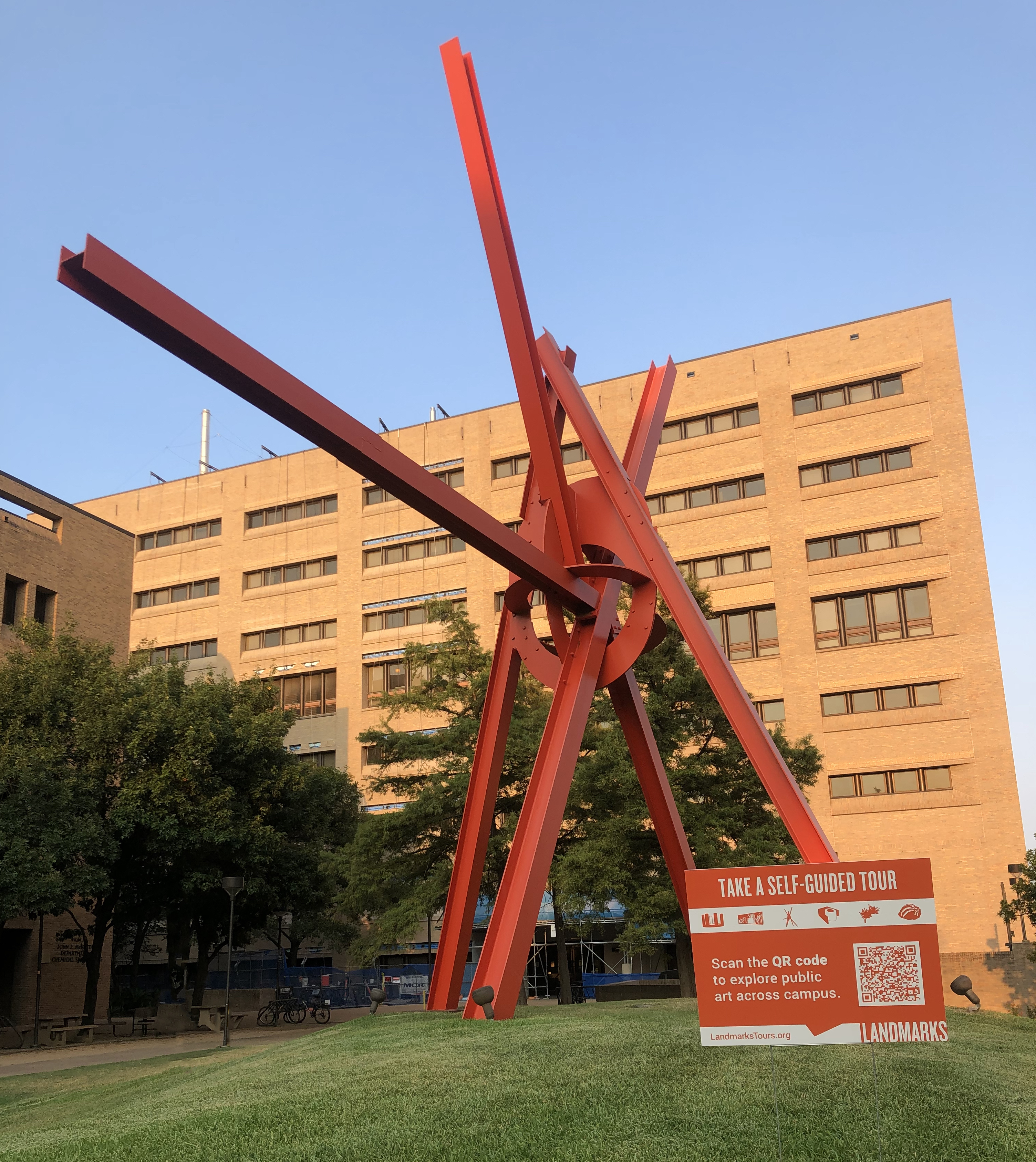A photo of Mark di Suvero's "Clock Knot" with a yard sign with information about virtual tours